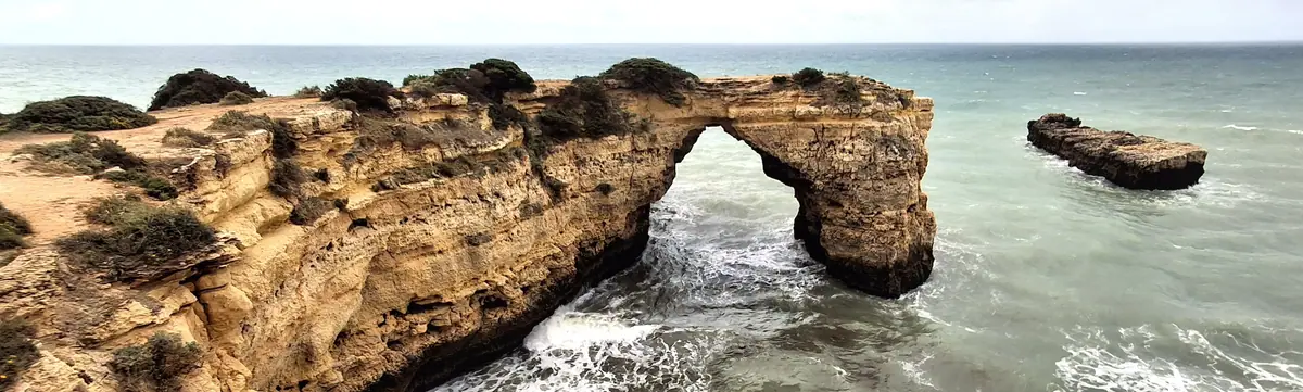 A natural rock arch standing in the sea off the cliffs