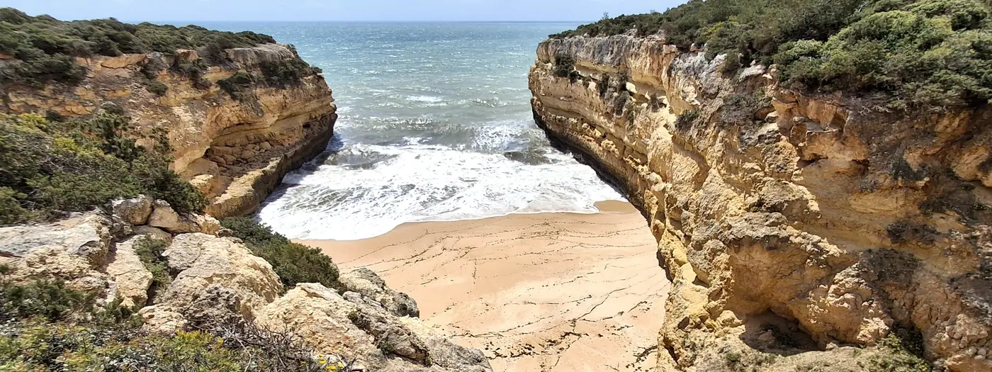 A hidden sandy cove between golden sandstone cliffs on the Algarve coast